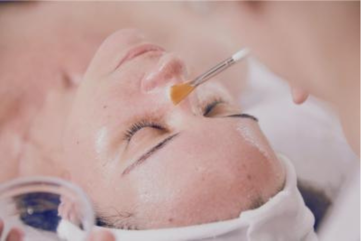 Aesthetic practitioner performing an IllumiFacial treatment on a client's face. The image captures the use of advanced technology to target pigmentation, improve skin tone, and enhance radiance, resulting in a clearer and more luminous complexion.